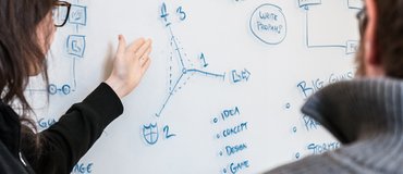 Designers talking design at a whiteboard